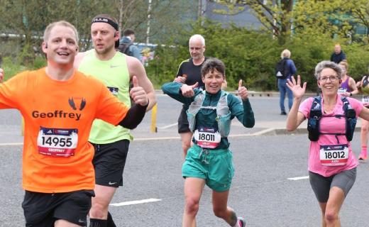 A photo of myself and others running with our thumbs up and smiling.